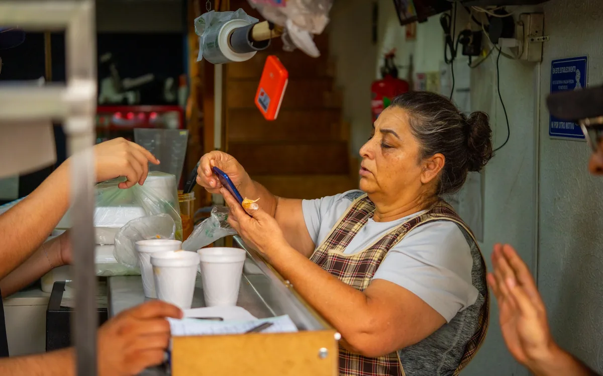 Vendedora anotando un pedido en su libreta, junto a los vasos que va a entregar