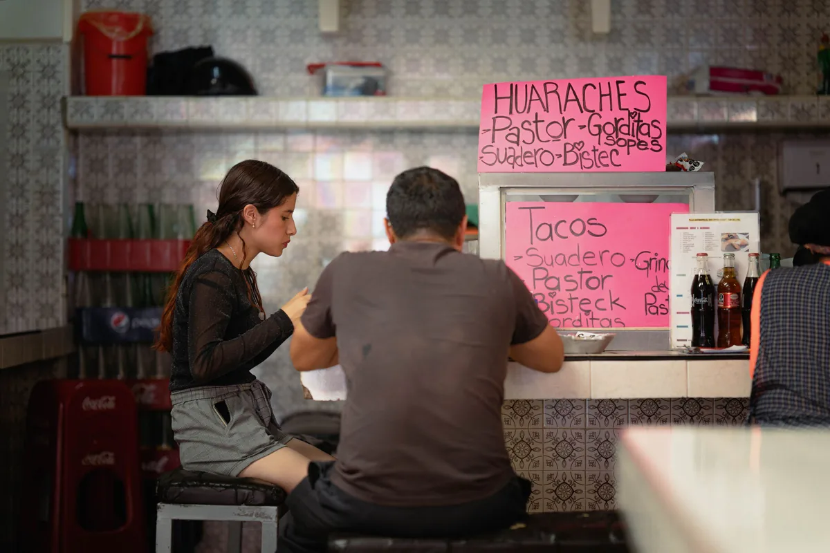Dos clientes comiendo en la barra de un puesto de comida de la Ciudad de México