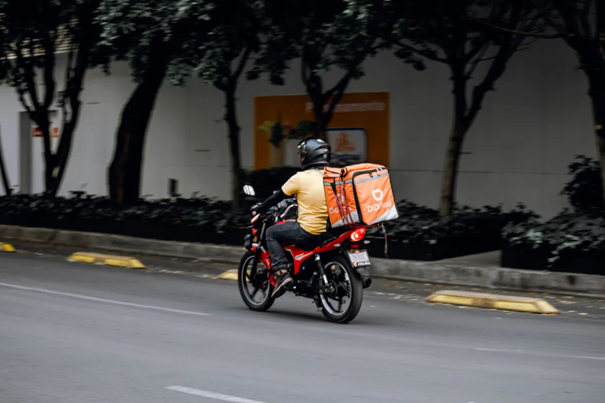 Repartidor en moto saliendo con la caja térmica a entregar un pedido