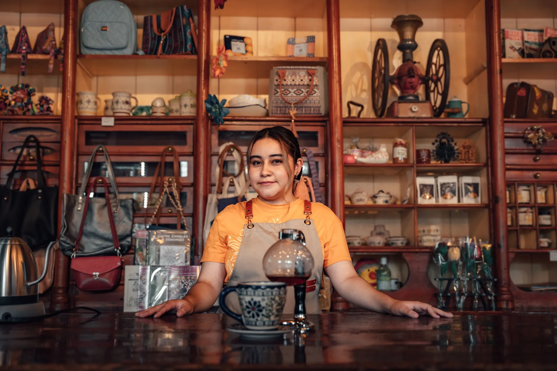 Dueña de una tienda mexicana detrás de su mostrador, con la loza y el género en los estantes de madera